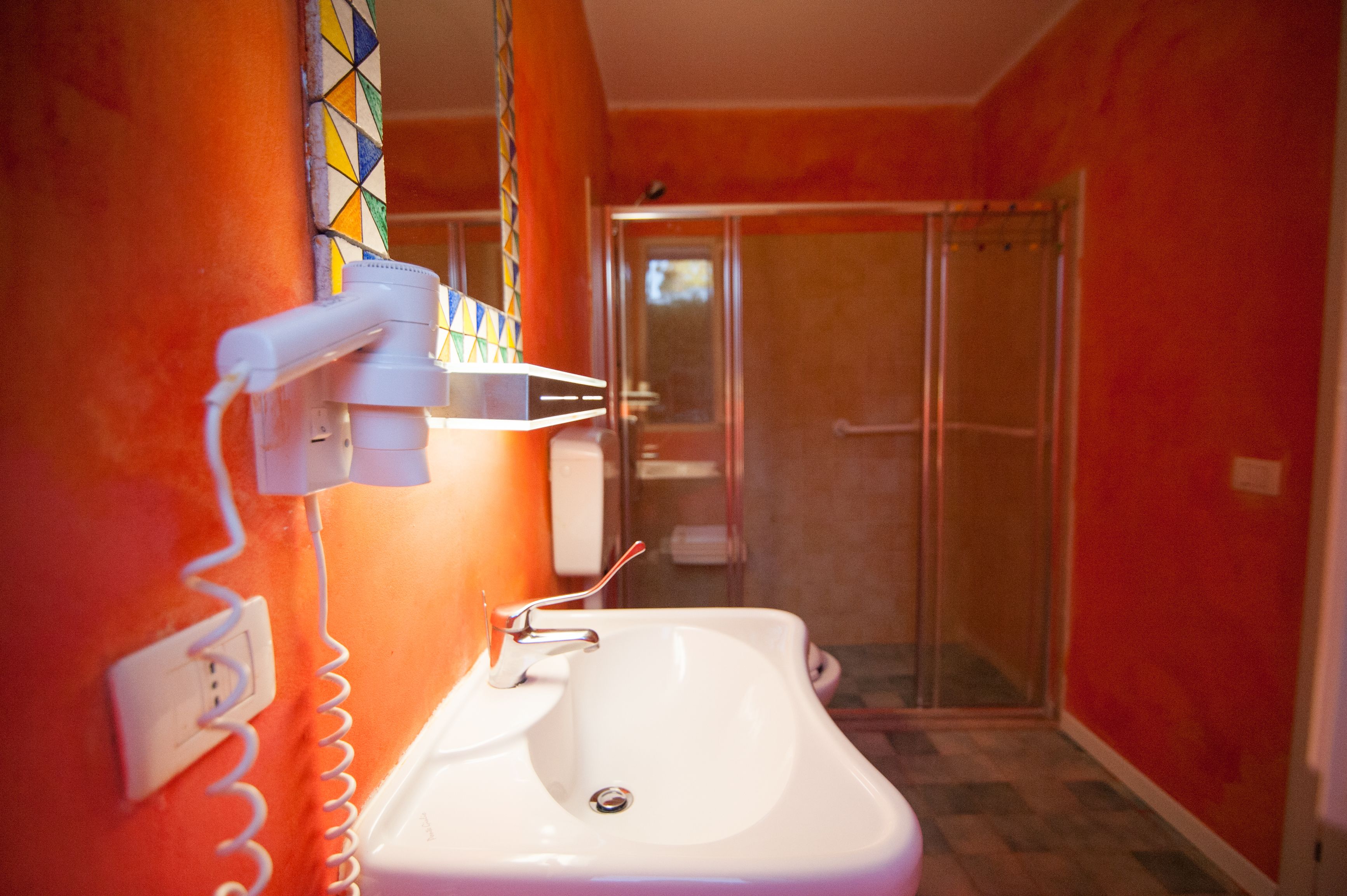Ein Badezimmer mit weißem Waschbecken, einer Dusche und einer gefliesten Wand.