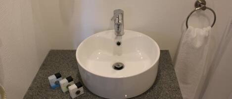 A bathroom with a white sink, a towel ring, and a granite countertop.