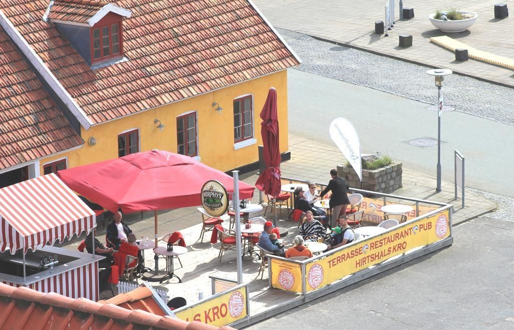 Un restaurante con terraza al aire libre, una sombrilla roja y un letrero que dice 'Terrasse Restaurant Pub Hirtshals Kro'.