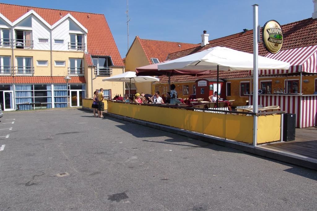A waterfront restaurant with outdoor seating, a yellow awning, and a Murphy's Irish Store sign.