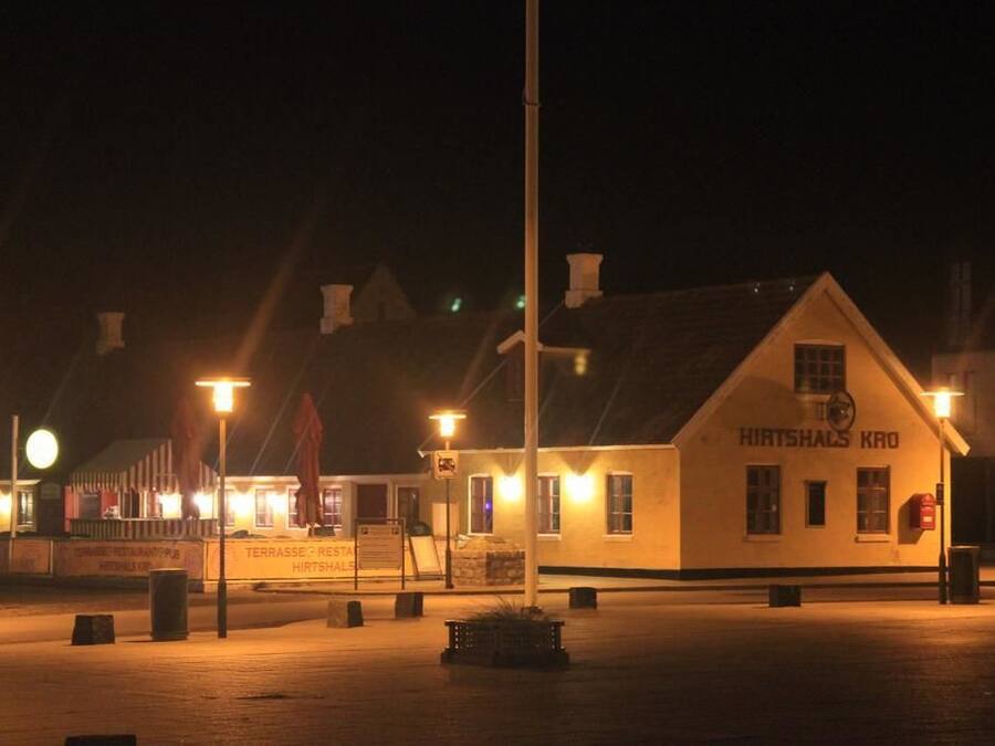 A building with a sign reading "HIRTSHAUS KRO" at night.