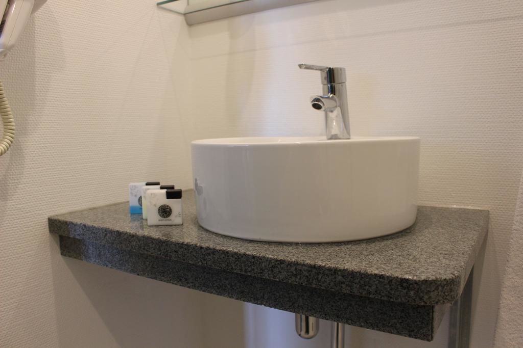 A bathroom with a white sink, a mirror, and a granite countertop.