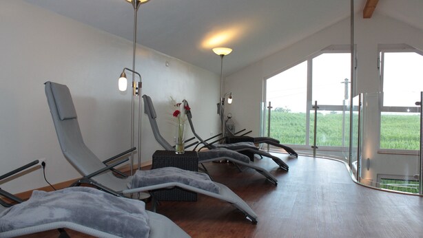 A room with multiple reclining chairs, a large window, and a view of a green field. - Hotel Landgasthof Ratz (Rheinau)
