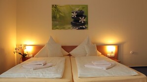 A double bed with white linens and towels, two bedside tables with lamps, and a painting of a zen garden on the wall. - Hotel Landgasthof Ratz (Rheinau)
