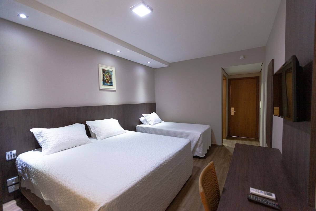 Una habitación de hotel con dos camas, un escritorio, una silla y una puerta.