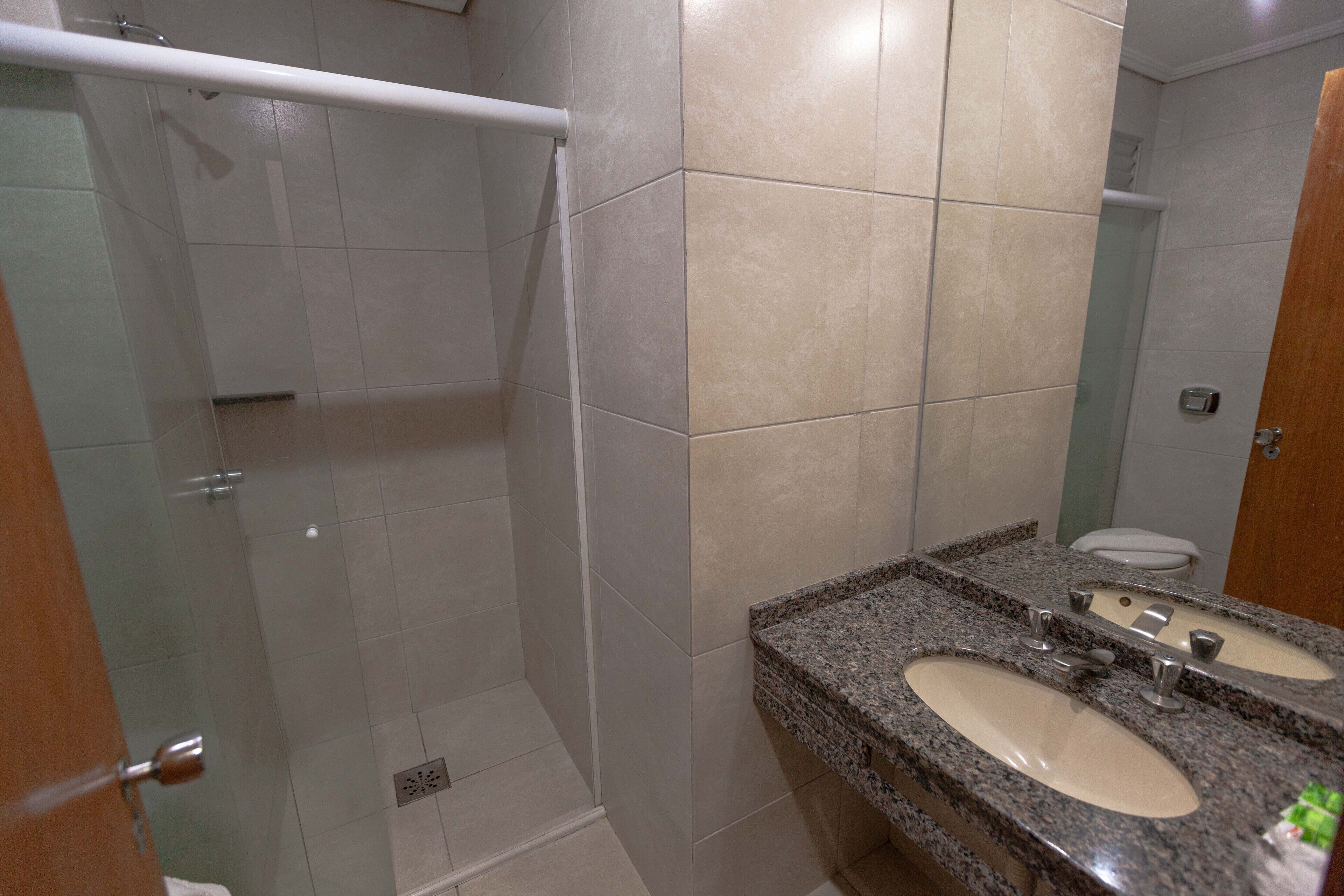 A bathroom with a shower, two sinks, and a mirror.