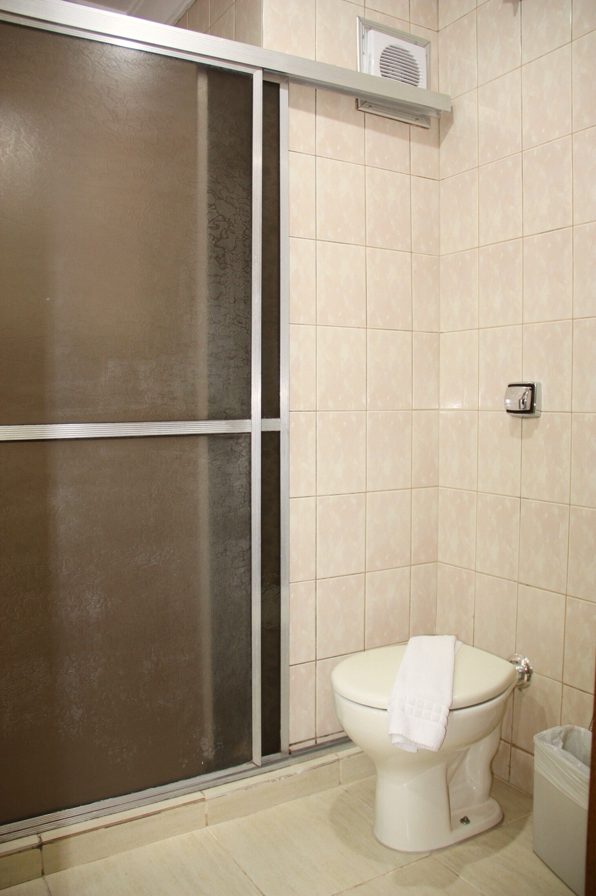 Un baño con inodoro, cabina de ducha y cubo de basura.