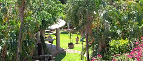 A garden with a gazebo, outdoor seating, and a variety of plants and flowers.