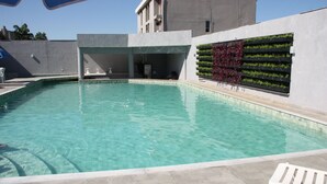A swimming pool with clear water, surrounded by a concrete deck and a wall with vertical gardens. - Hotel Foz do Iguaçu (Foz do Iguaçu)