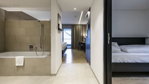 Ein modernes Hotelzimmer mit separater Dusche, einem Bett, einem Schreibtisch und Blick ins Freie.