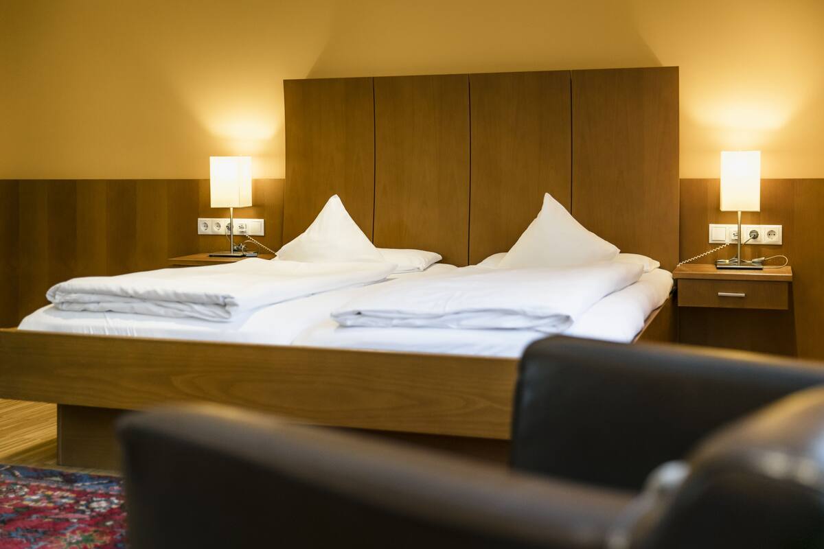 A hotel room with a double bed, two bedside tables with lamps, and a wooden headboard.