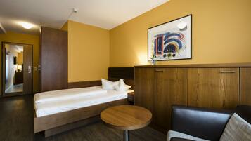Quarto de hotel com cama, mesa redonda, sofá e um quadro na parede.