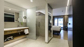 Un baño de hotel moderno con un espejo grande, un secador de pelo incorporado y una zona de ducha.