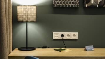 Una habitación moderna con escritorio, lámpara, silla y una pared decorada con motivos.
