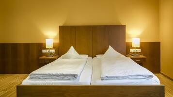 A double bed with two bedside tables, each with a lamp, in a room with wooden paneling and a warm color scheme.