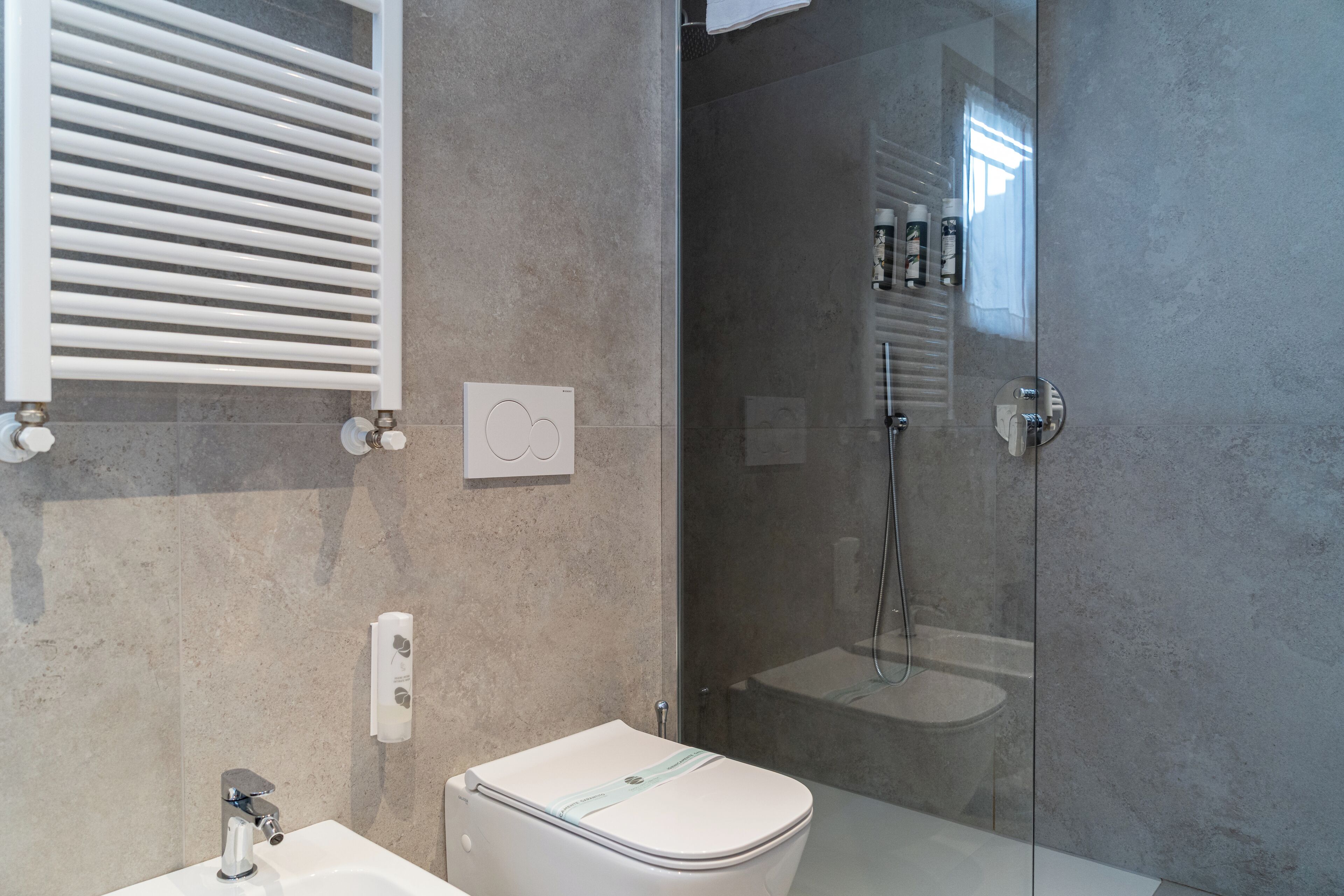 Un baño moderno con inodoro, lavamanos y cabina de ducha de vidrio.