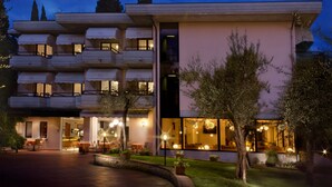 Un hotel de varios pisos con balcones, una entrada bien iluminada y un jardín ajardinado.