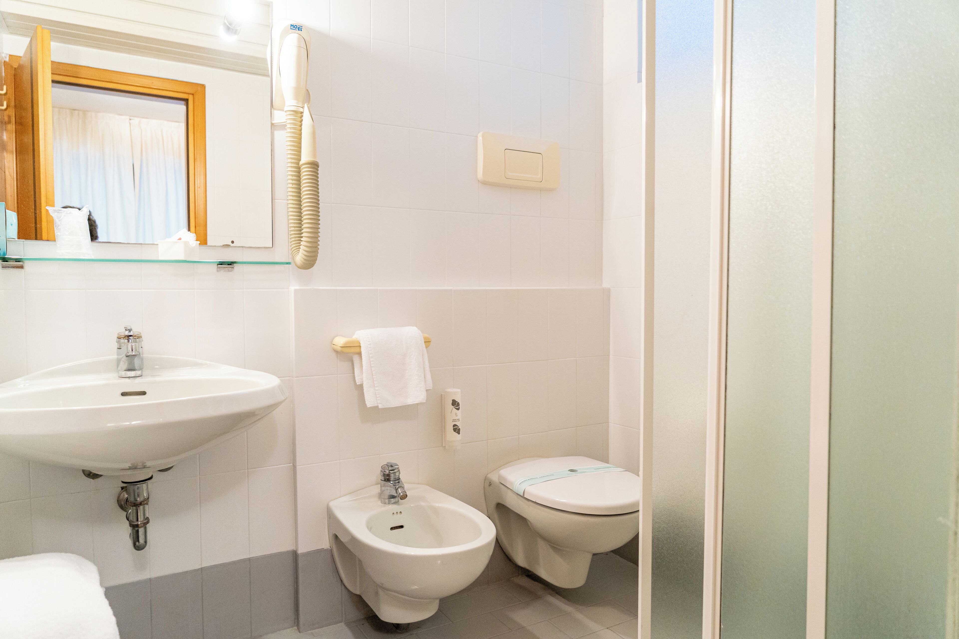 A bathroom with a sink, bidet, and toilet.