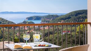 A balcony with a table, a book, a pitcher of water with lemon slices, and a glass of water. - Salvator Villas & Spa Hotel (Parga)