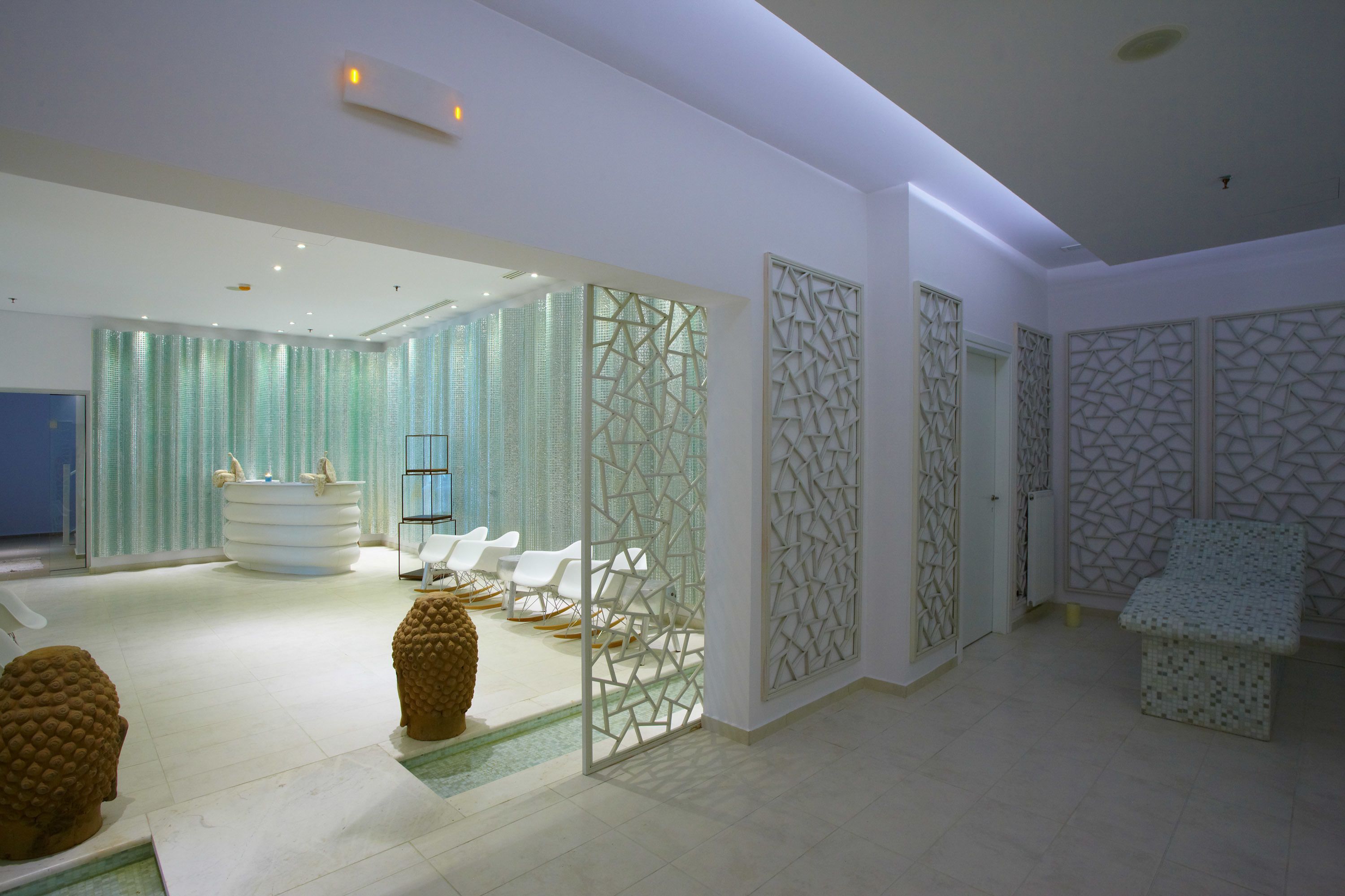 A modern spa room with a reception desk, seating area, and decorative wall panels.