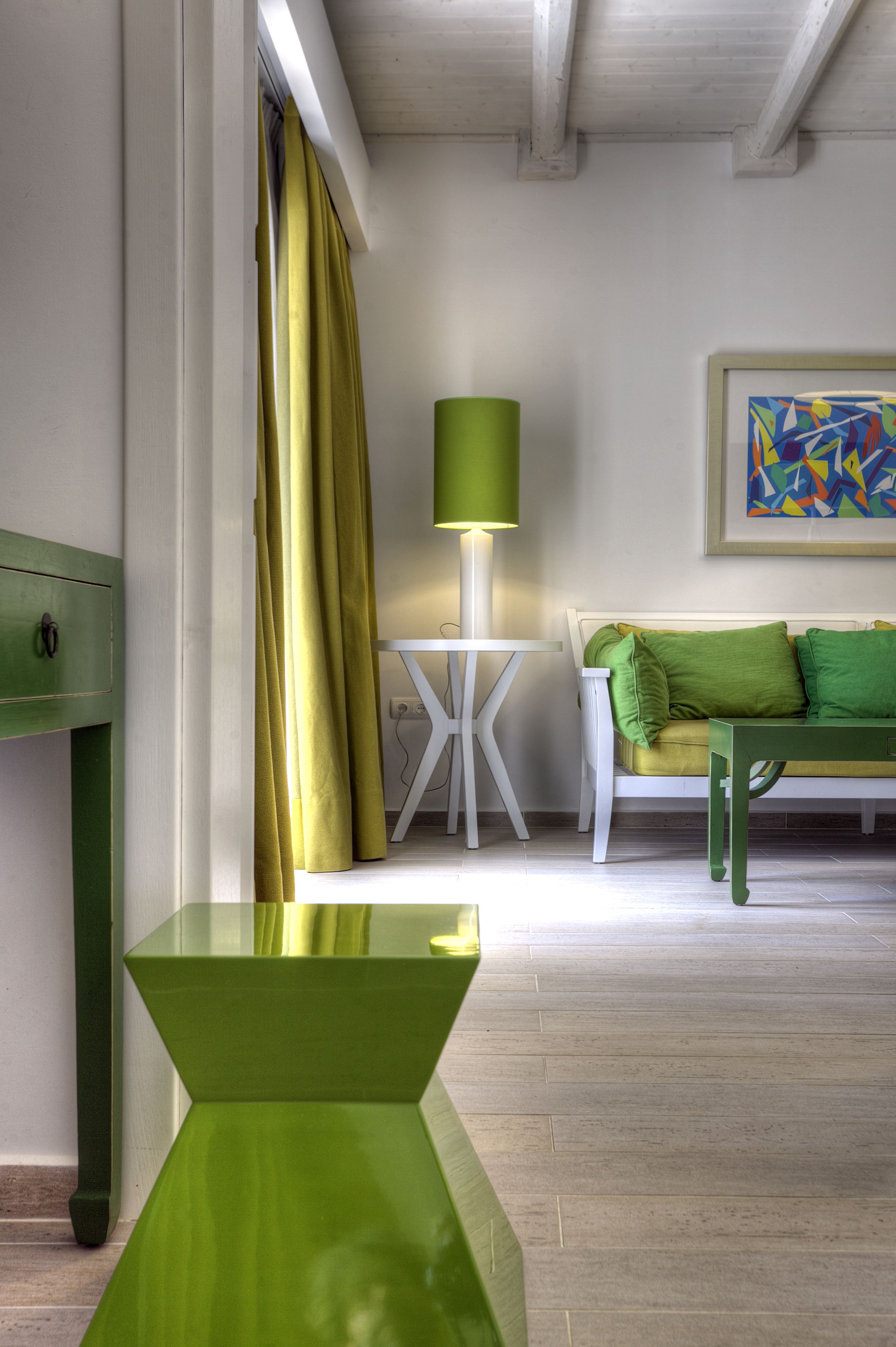 A modern living room with a green sofa, a white side table, and a green lamp.