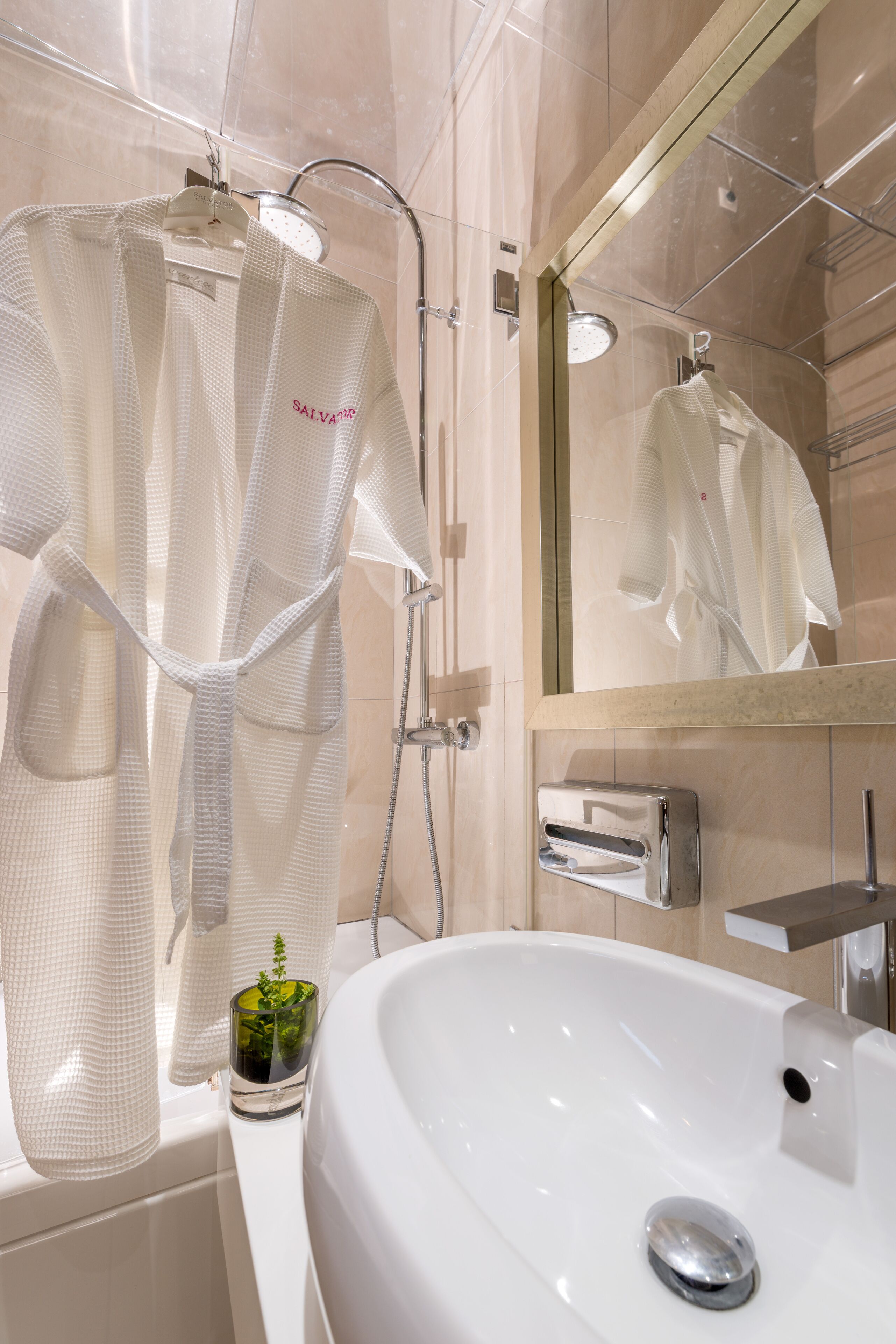 Ein modernes Badezimmer mit einem großen Spiegel, einer weißen Badewanne und einer Duschkabine, in der ein Bademantel hängt.