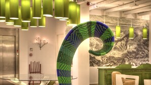 A modern interior with a unique green and blue chair, green pendant lights, and a green cabinet. - Salvator Villas & Spa Hotel (Parga)