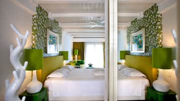 A mirrored room with a bed, green nightstands, and a green lamp.