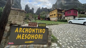 A sign for private parking and guesthouse named Archontiko Mesohori, with a stone wall and a car parked nearby. - Archontiko Mesohori (Kalabaka)