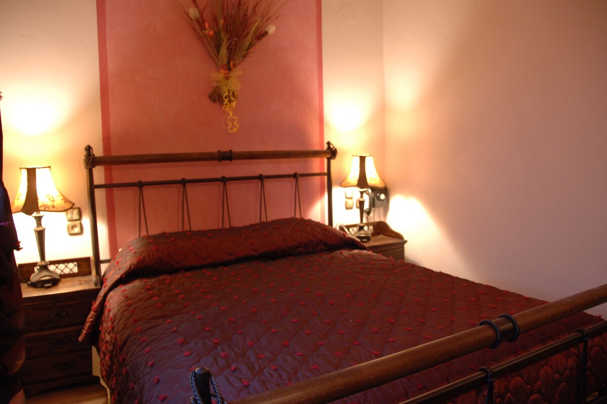A bed with a headboard, two bedside tables with lamps, and a wall-mounted decoration.