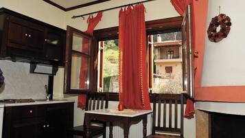 Un comedor con una mesa y sillas, una ventana con cortinas rojas y vistas a un edificio.