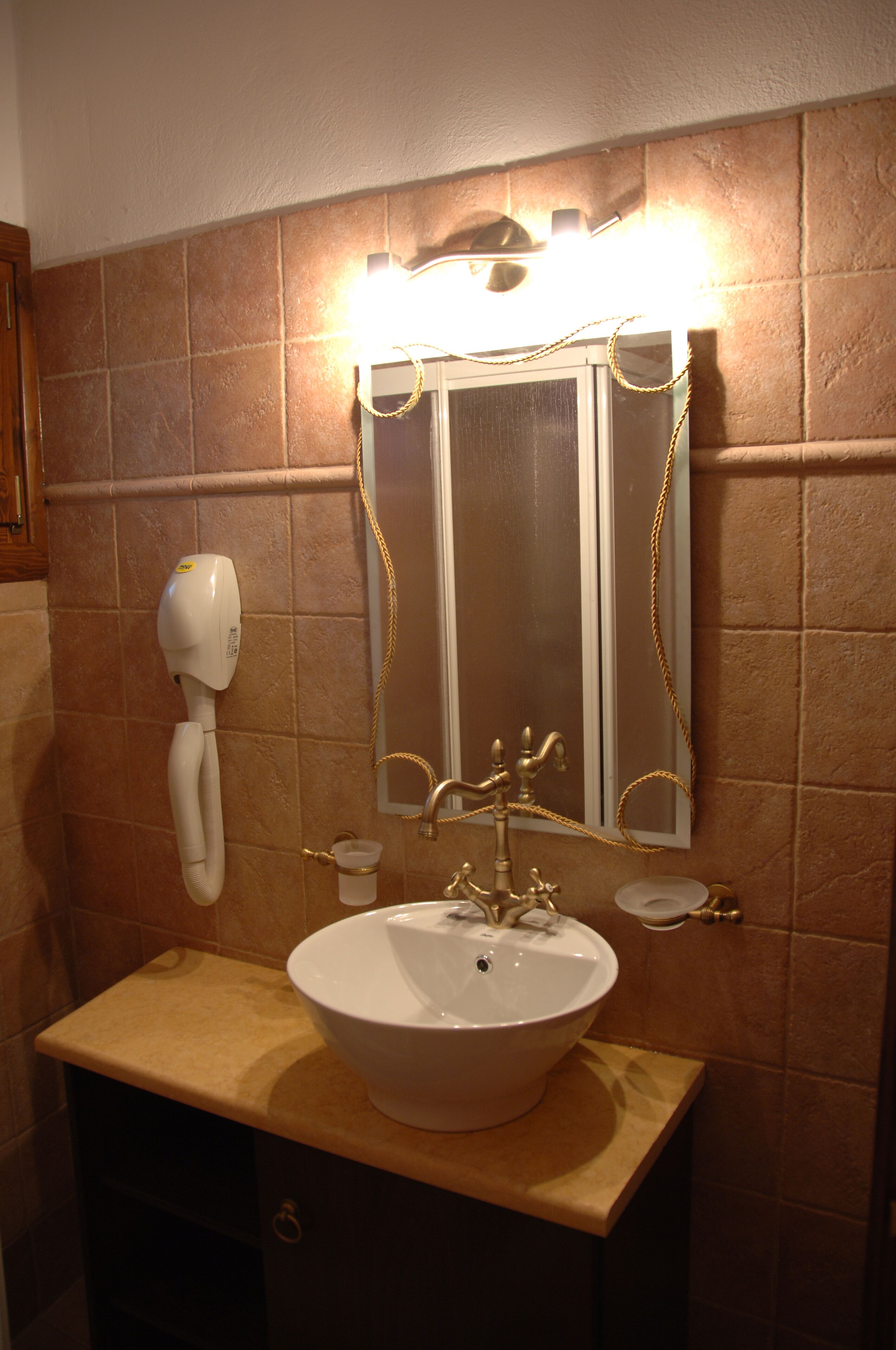 Un baño con un espejo grande, un lavamanos y un secador de pelo montado en la pared.