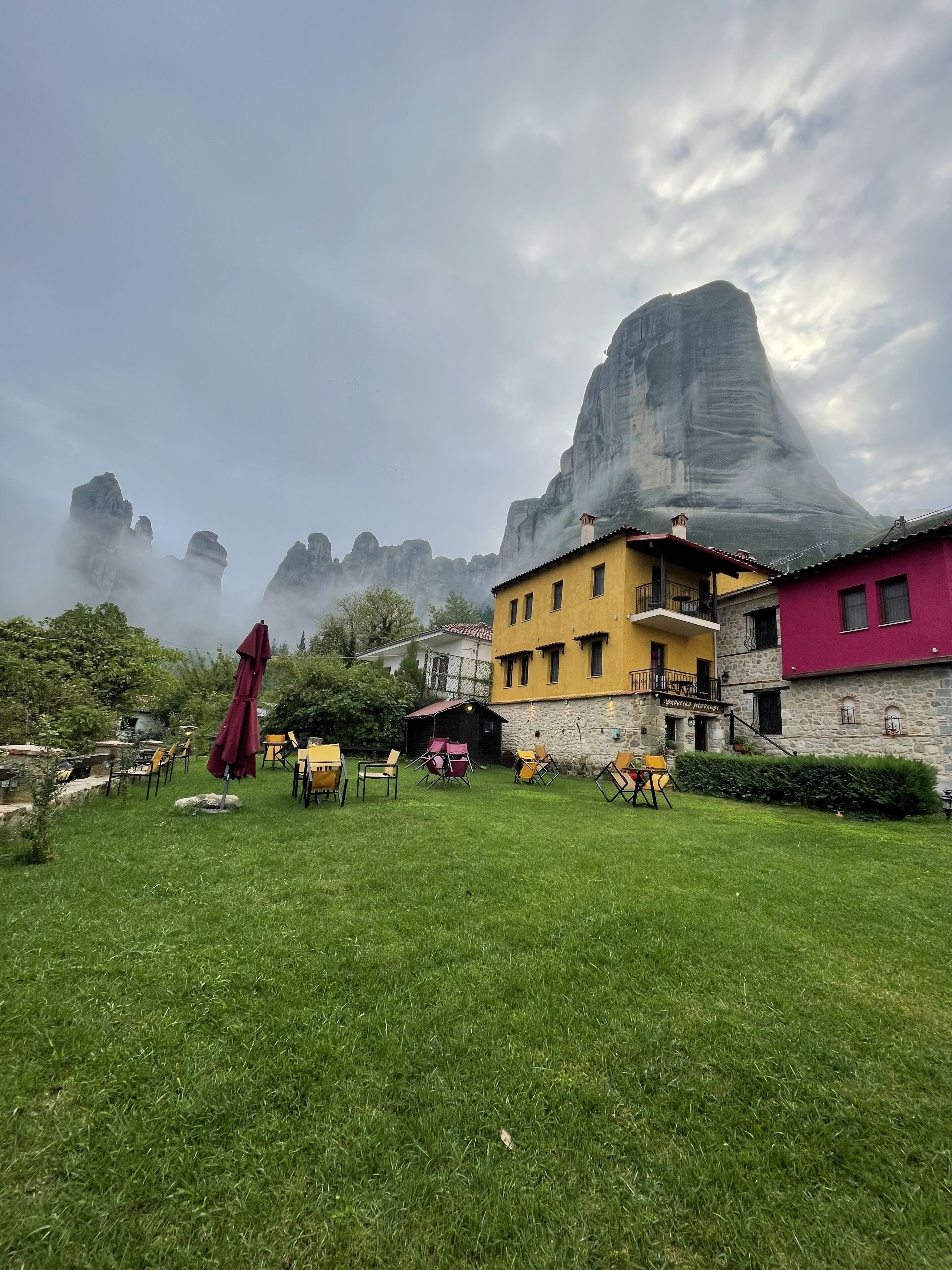 Un espacio al aire libre con césped, mobiliario exterior y una gran montaña al fondo.