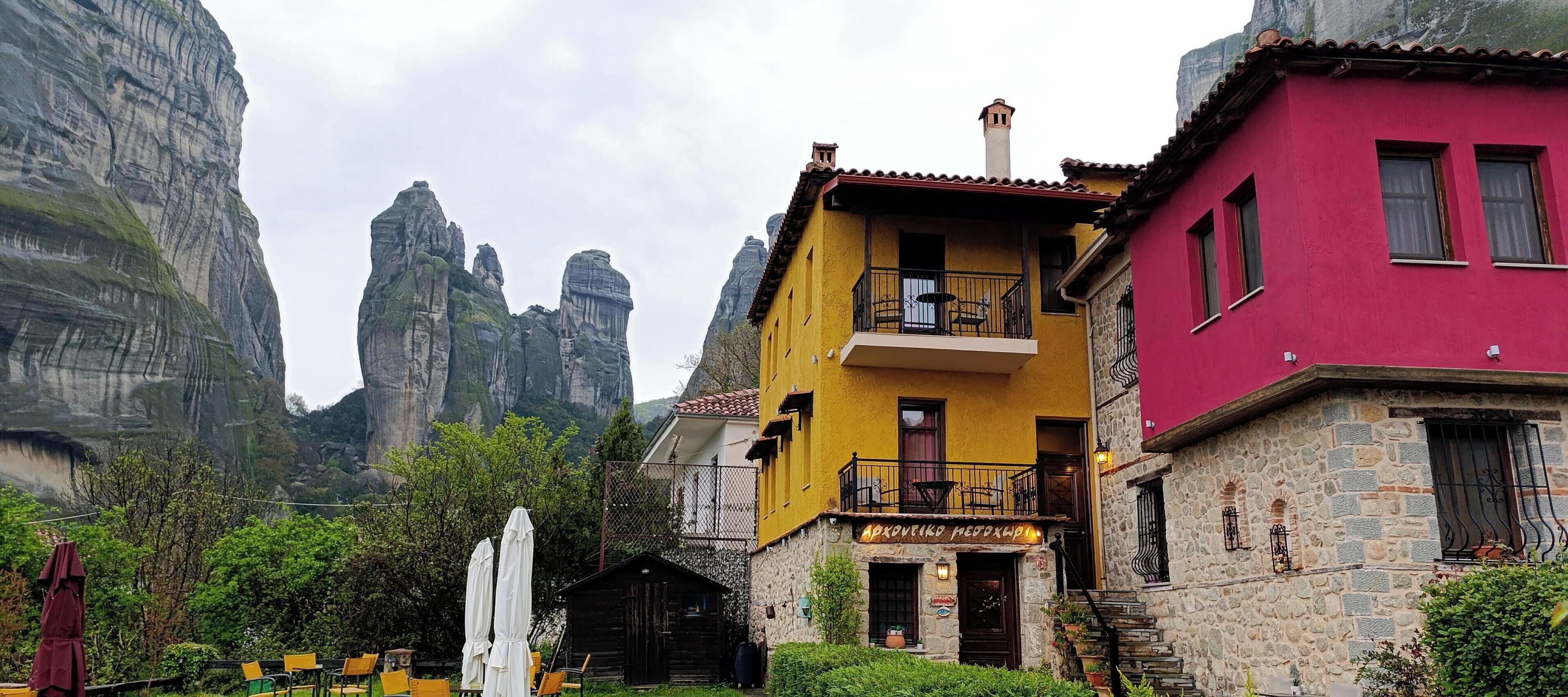 Un edifici amb façana de color groga i rosa, un balcó i una base de pedra.