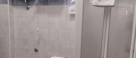 Un baño con inodoro, bidé y ducha con cerramiento de vidrio.