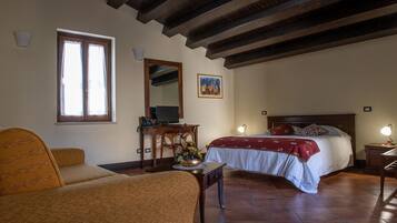 Un dormitorio con cama, escritorio, silla, ventana y un cuadro en la pared.