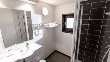 A bathroom with a white sink, mirror, and a glass-enclosed shower.