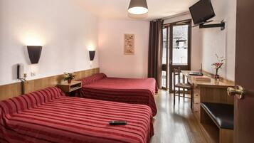 Habitación de hotel con dos camas, un escritorio, una silla, un televisor y una ventana con cortinas.