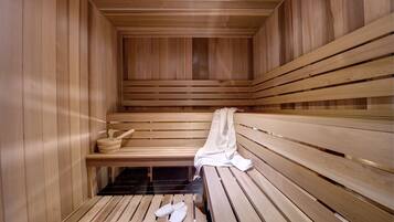 A wooden sauna with benches and a bench seat, a bench seat with a towel and a pair of slippers, and a bench with a towel.