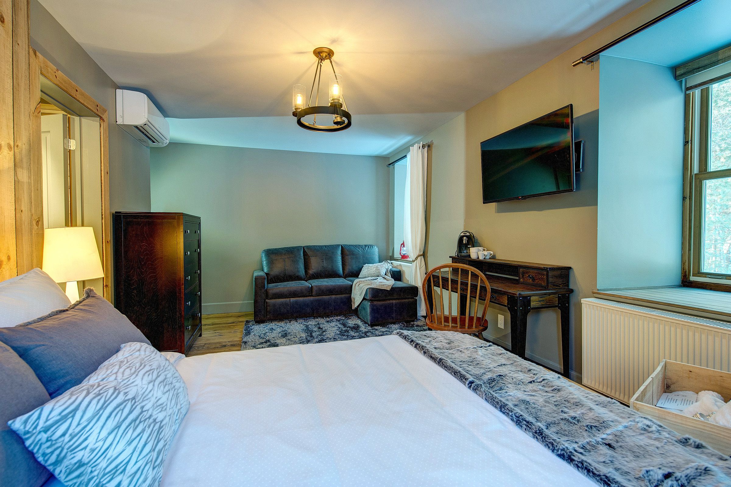 Un dormitorio con una cama grande, un escritorio, una silla, un sofá y un televisor.