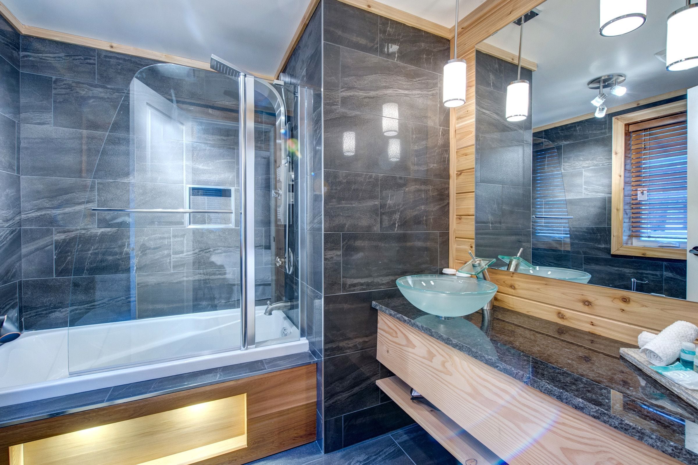 A modern bathroom with a glass-enclosed shower, a wooden vanity, and a large mirror.