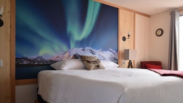 Ein Hotelzimmer mit einem Bett, einer Wanduhr und einem Fenster mit Vorhängen.