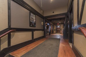 Un pasillo con suelo de madera, una pared blanco y negro con un cartel, y un letrero que indica el escenario principal.