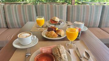 A breakfast setting with a table, plates of food, and drinks.