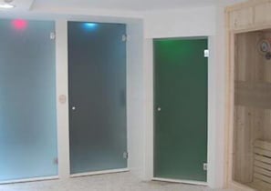 Tres puertas con paneles de vidrio esmerilado, una con un tinte verdoso, y una puerta de madera con un diseño circular.