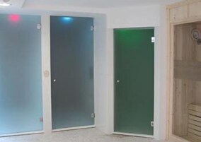Tres puertas con paneles de vidrio esmerilado, una con un tinte verdoso, y una puerta de madera con un diseño circular.