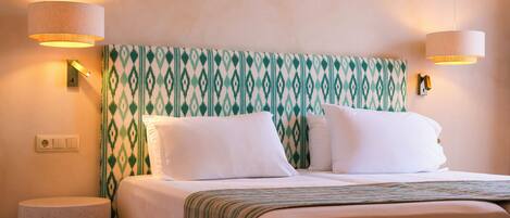 A hotel room with a bed, two wall-mounted lamps, a power outlet, and a textured wall.