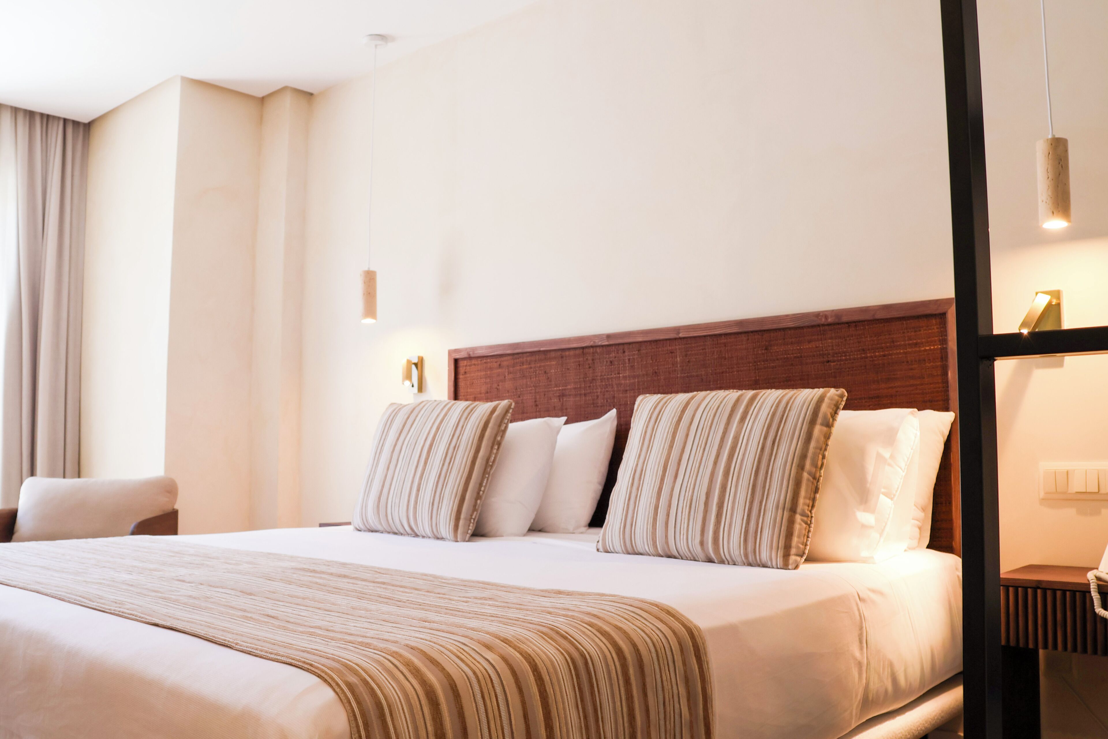 Een hotelkamer met een groot bed, een houten hoofdeinde en een nachtkastje met een lamp.