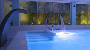 An indoor swimming pool with a water feature, a metal handrail, and a glass wall with a view of trees. - Del Mar Hotel & Spa (El Puerto de Santa Maria)