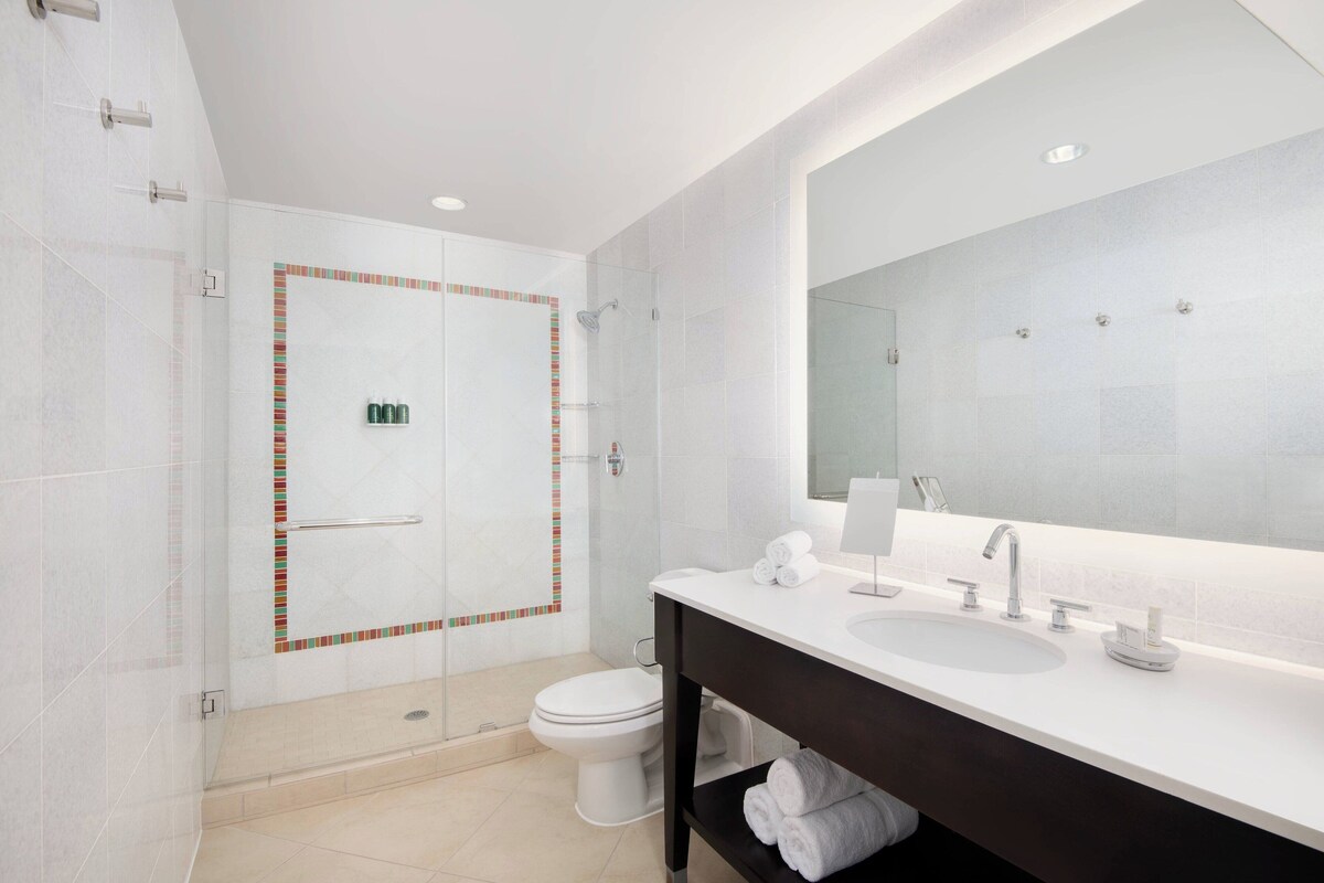 A modern bathroom with a glass-enclosed shower, a white sink, and a large mirror.